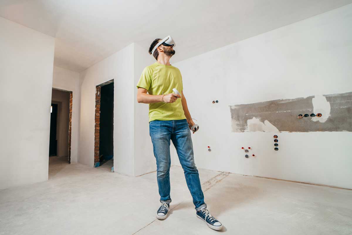 Man wearing virtural reality headset in a room that is under construction to see how the space will look once it is finished.